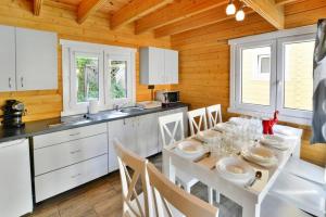 a kitchen with a white table and white chairs and a kitchen with white cabinets at Holiday resort with Pool Whirlpool Sauna Ustronie Morskie in Ustronie Morskie