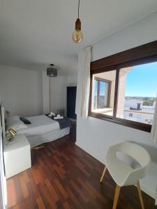 um quarto com uma cama, uma janela e uma cadeira em Atico TERRAZA DEL CARMEN em Salobreña