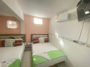 a small room with two beds with green sheets at House Marfito Airport in Cartagena de Indias