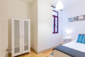 a white bedroom with a bed and a cabinet at Boho House Terrace in Porto