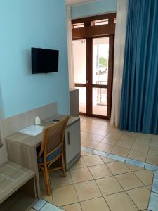 Habitación con escritorio con silla y TV. en La Conchiglia en Sperlonga