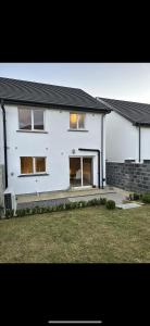 a white house with its door open in a yard at Home in Kilmuckridge in Wexford