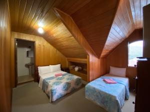 a room with two beds in a wooden room at Pousada Recanto da Giovana in Campos do Jordão