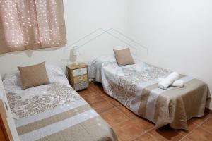 1 dormitorio con 2 camas y mesa con lámpara en Villa Zapatilla, en Chiclana de la Frontera