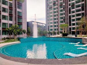 a swimming pool with a fountain in front of buildings at Cubic Botanical Studio 情侣体验民宿电影院的浪漫 in Kuala Lumpur