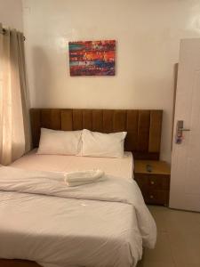 uma cama com lençóis brancos e uma cabeceira de madeira em Mph mini em Lagos