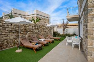 Un patio con sillas y mesas y una sombrilla. en Aphrodites Luxury pearls 1, en Pitsidia
