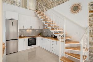 una cocina con armarios blancos y una escalera de caracol en Aphrodites Luxury pearls 1, en Pitsidia