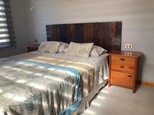 1 dormitorio con 1 cama con cabecero de madera y mesita de noche en Cabaña de campo, en Valdivia