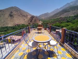 a table and chairs on a balcony with mountains at Atlas Haven in Imlil