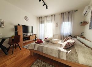a bedroom with a bed and a desk and a television at APARTMAN 52 - Privatni parking za goste in Novi Sad