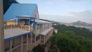 a building with a blue roof and a view of the ocean at Sunset Gardens Guesthouse in Charlotte Amalie