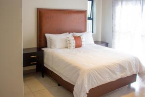 a bedroom with a bed with white sheets and pillows at 16 Elizabeth Place - Luxury Apartments, Free Wi-Fi in Midrand
