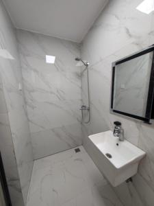 a white bathroom with a sink and a mirror at OV HOMES in Dar es Salaam