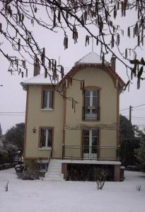 uma casa com neve no chão em frente dela em la villa des chats em Andrésy