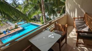 a balcony with a table and a swimming pool at Charming apartment close to beach & amenities - Appartement de charme proche plage in Flic-en-Flac