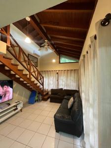 ein Wohnzimmer mit einem schwarzen Ledersofa und einem TV in der Unterkunft B12 Casa em Maresias condomínio a 50 metros da praia in Maresias