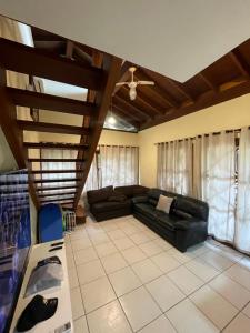 uma sala de estar com um sofá de couro preto e tectos de madeira em B12 Casa em Maresias condomínio a 50 metros da praia em Maresias