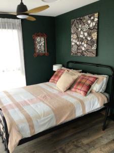 a bedroom with a bed with green walls and a fan at Beautifully Elevated Treehouse Apartment in Buderim