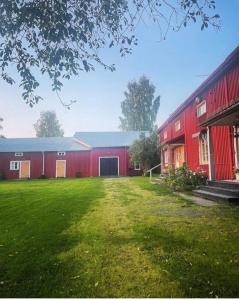 Um celeiro vermelho com um jardim de relva à frente. em Gamla gården i Ersmark Umeå em Umeå