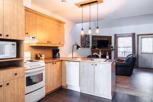 a kitchen with white appliances and wooden cabinets at La petite saisonnière in Mont-Tremblant