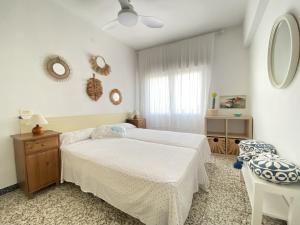 een witte slaapkamer met een bed en een tafel bij Apartamento familiar a 200m de la playa in Alcossebre