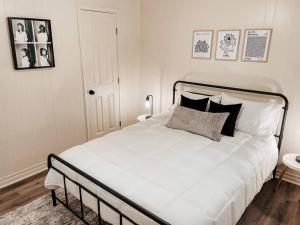 uma cama branca com almofadas pretas num quarto em Artist's Bungalow - 1/2 mi from Covington Square em Covington