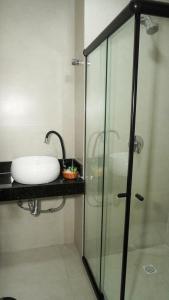 uma casa de banho com um lavatório e uma cabina de duche em vidro. em Pousada Flor de Magnólia em Porto de Galinhas