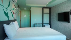 a bedroom with a large white bed with a flat screen tv at Pousada Flor de Magnólia in Porto De Galinhas