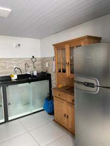a kitchen with a stainless steel refrigerator and wooden cabinets at Pousada Alto da Maroca in São Francisco do Sul
