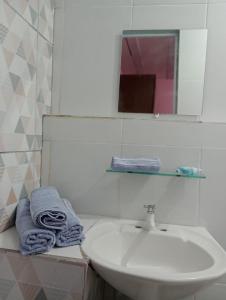 a bathroom with a sink and a mirror and towels at Apartamento Acochegante in Manaus
