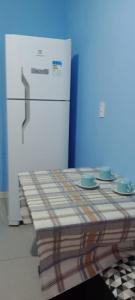 a kitchen with a table with plates and a refrigerator at Apartamento Acochegante in Manaus