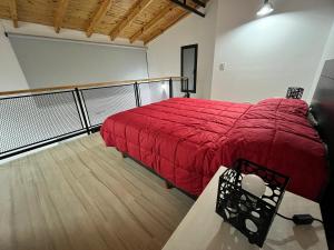 um quarto com uma cama com um cobertor vermelho em Nelson´s Place em Esquel