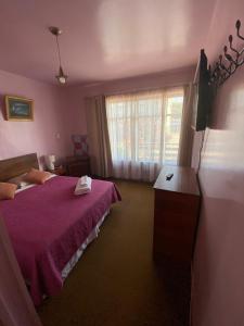 1 dormitorio con cama morada y ventana en Hospedaje Rios en Osorno