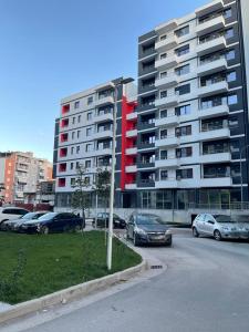 a parking lot with cars parked in front of a large building at Melody Apartment in Korçë in Korçë