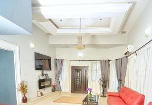 a living room with a red couch and a tv at Appiah's Royal Suites in Accra