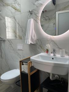 a bathroom with a sink and a mirror and a toilet at Sunny City Center Apartment in Lezhë