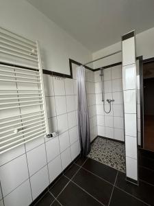 een badkamer met een douche en witte betegelde muren bij Temporalis Unterkunft in Langerwehe