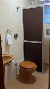 a bathroom with a toilet with a glass shower door at Pousada Recanto da Giovana in Campos do Jordão