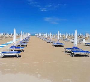 a row of lounge chairs and umbrellas on a beach at Alvin Comfort Hotel in Durrës