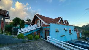 a blue house with a balcony and a car at Pousada Recanto da Giovana in Campos do Jordão