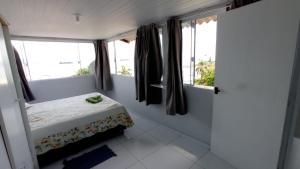 a small bedroom with a bed and windows at Pousada Alto da Maroca in São Francisco do Sul