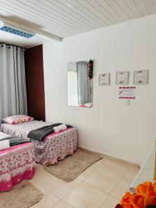 two beds in a room with white walls and a mirror at Hostel das Flores in Belém