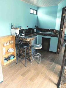 Una cocina con encimera y taburetes en una habitación. en Casa del Árbol, en Quepos