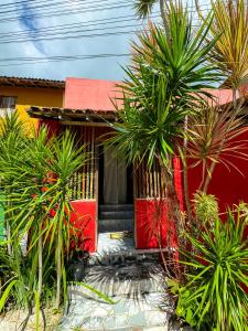 una casa roja con palmeras delante en Casa da Cosmira, en Trancoso