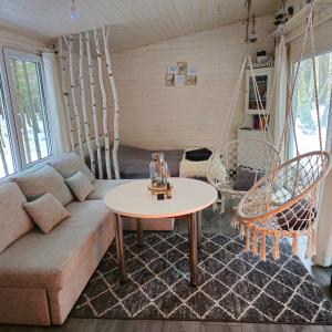 a living room with a couch and a table at Miško sielos namelis su pirtele in Aukštelkė