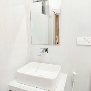 a white bathroom with a sink and a mirror at The Paddy in Kottawa