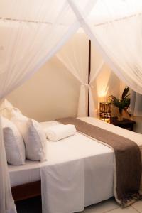 un dormitorio con una cama con sábanas y almohadas blancas en Casa da Cosmira, en Trancoso