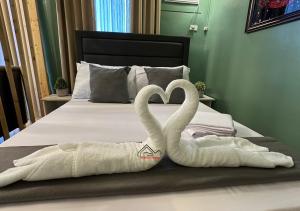 two towels shaped like swans sitting on a bed at Palawan 1BR Summer Get-away Deluxe with Balcony FREE Pool and Gym - T2 6 Diamond in Puerto Princesa City