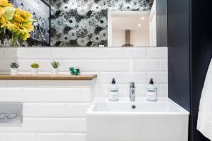 W białej łazience znajduje się umywalka i lustro. w obiekcie Cozy 3 Bedroom Terrace Cottage in Epsom w mieście Epsom